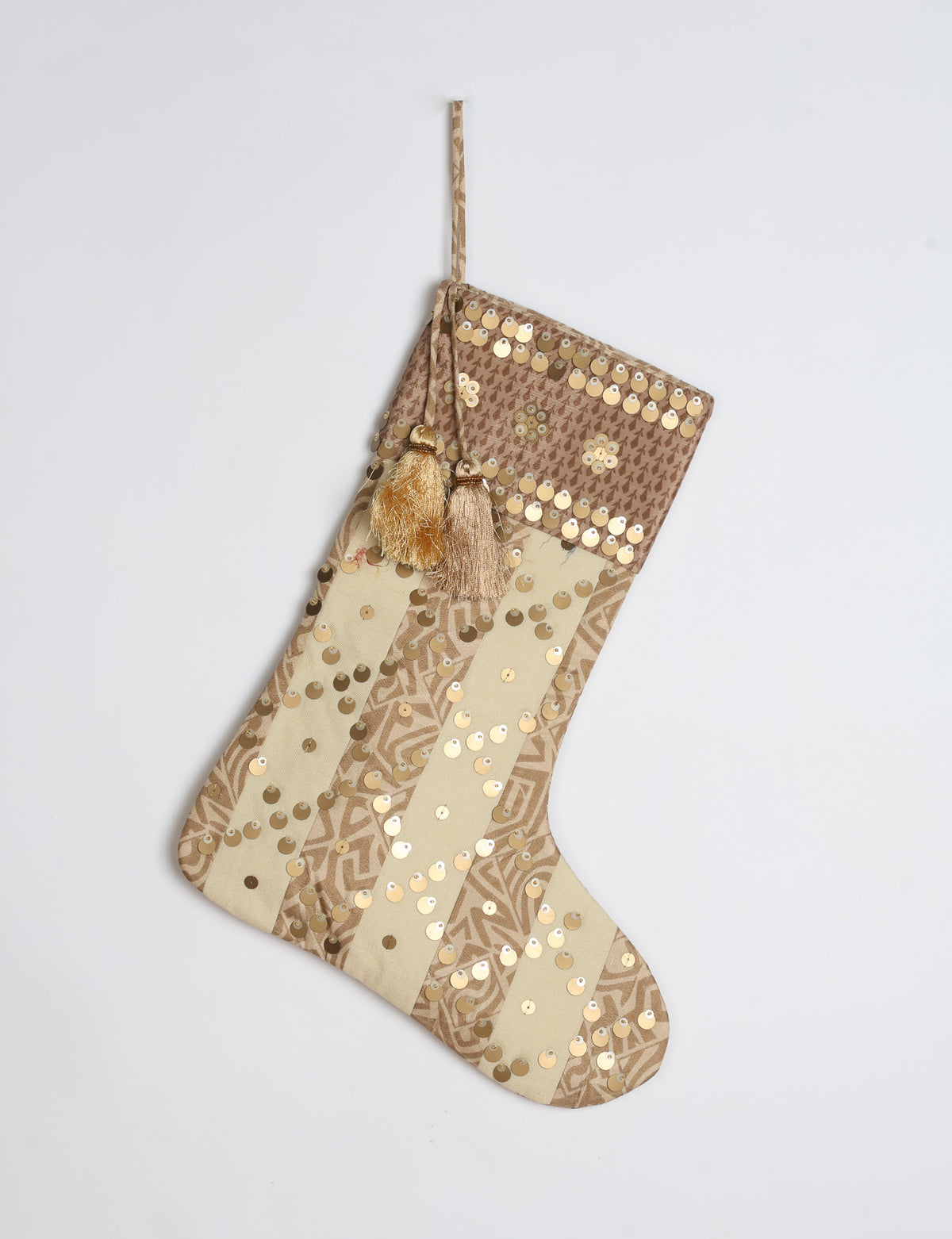 Christmas stocking with beige and brown vertical stripes, floral pattern, gold sequins, and two tassels on hanging loop