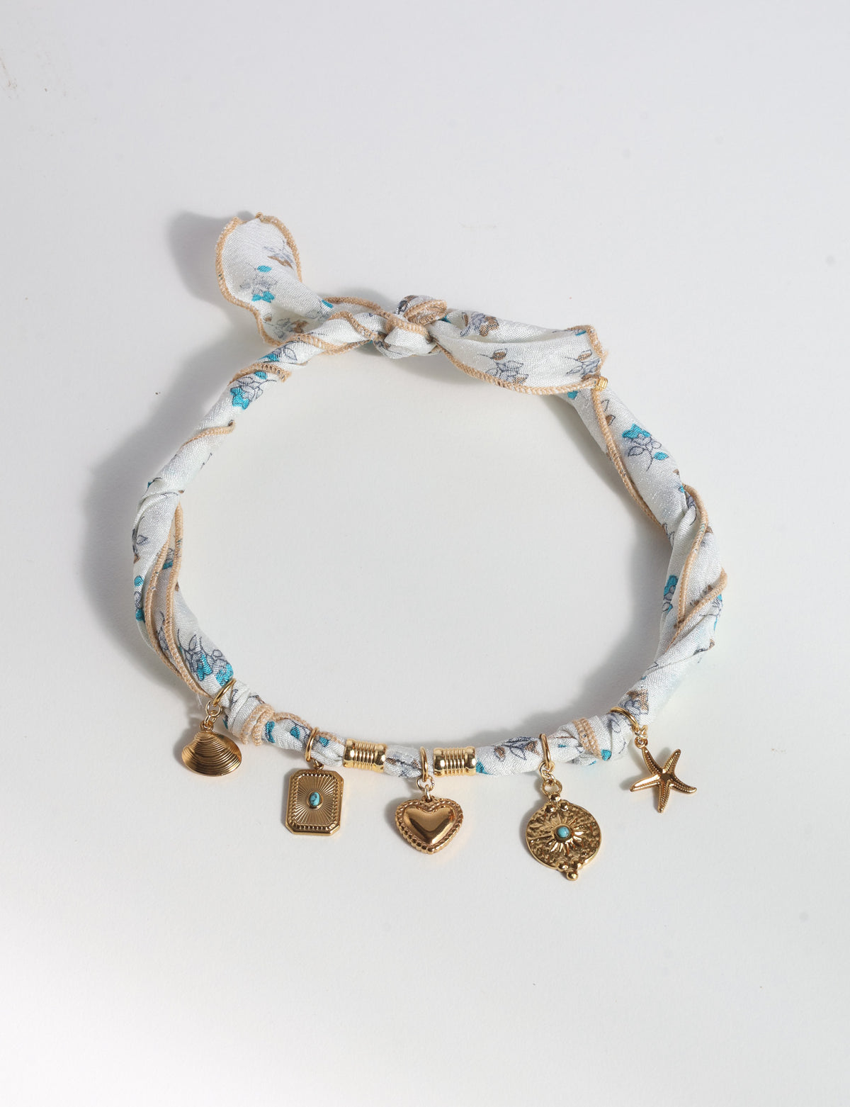 White tropical patterned bandana necklace with gold-tone shell, heart, starfish, and turquoise-accented charms, knotted closure