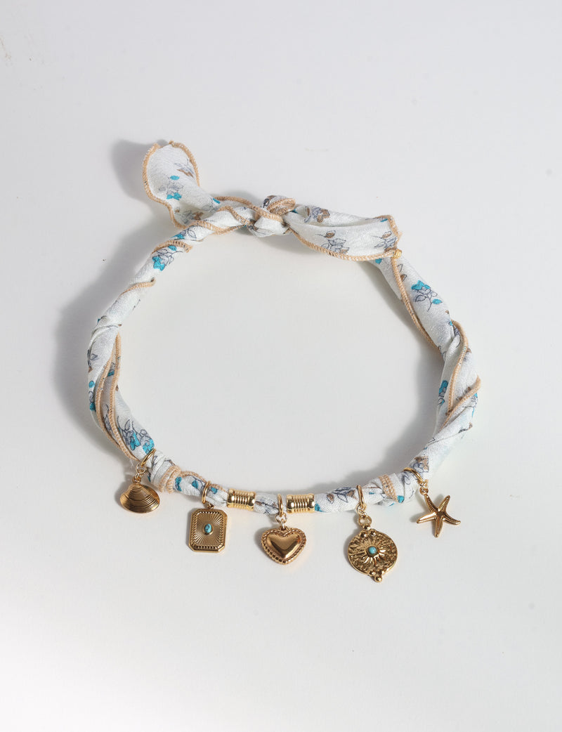White tropical patterned bandana necklace with gold-tone shell, heart, starfish, and turquoise-accented charms, knotted closure