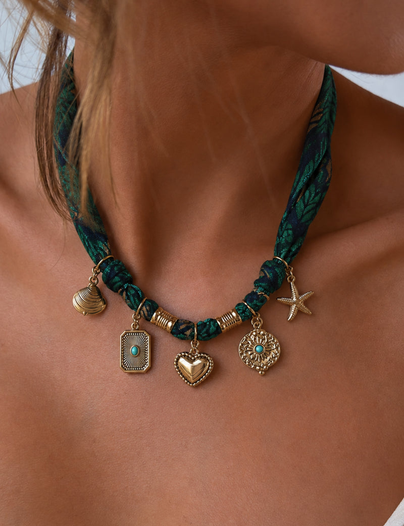 Green floral patterned bandana necklace worn by model with gold-tone charms including heart, starfish, and shell pendants