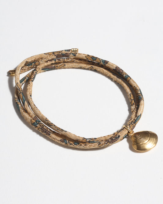 Adjustable slim cord bracelet with gold-plated stainless steel shell charm inspired by upcycled women’s clothing, sustainable women’s clothing, eco friendly clothes, recycled sustainable fashion, carbon neutral clothing, and environment friendly clothing values.
