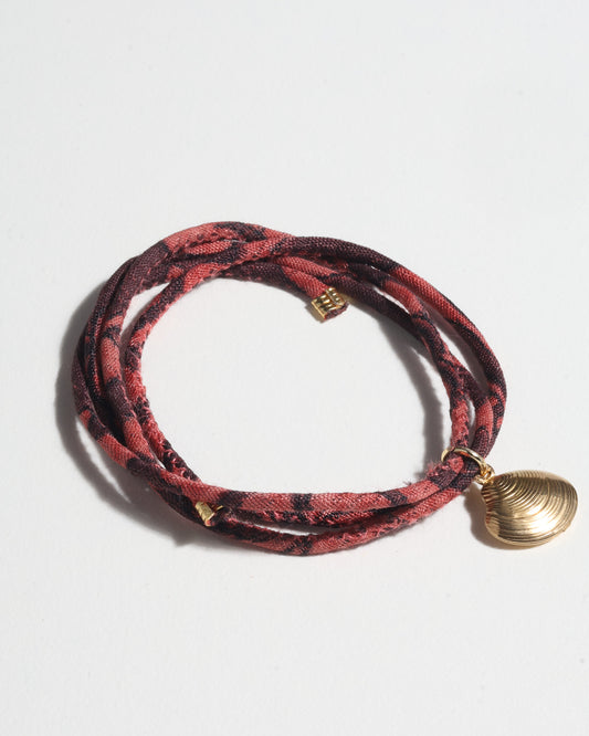 Adjustable slim cord bracelet with gold-plated stainless steel shell charm inspired by upcycled women’s clothing, sustainable women’s clothing, eco friendly clothes, recycled sustainable fashion, carbon neutral clothing, and environment friendly clothing values.