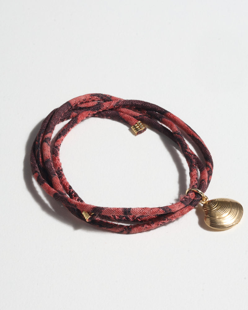 Brown and dark red abstract patterned cord bracelet with gold-tone shell charm, shown flat on white background
