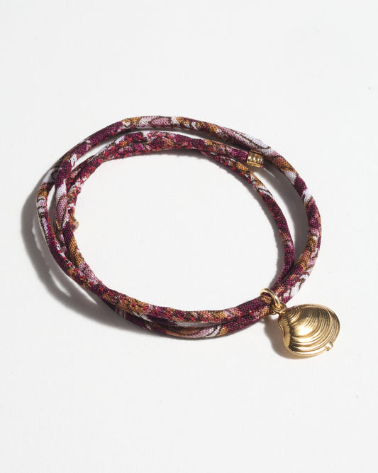 Adjustable slim cord bracelet with gold-plated stainless steel shell charm inspired by upcycled women’s clothing, sustainable women’s clothing, eco friendly clothes, recycled sustainable fashion, carbon neutral clothing, and environment friendly clothing values.