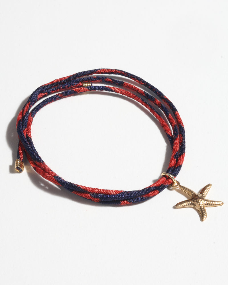Red and navy blue cord bracelet with gold starfish charm, shown flat on white background