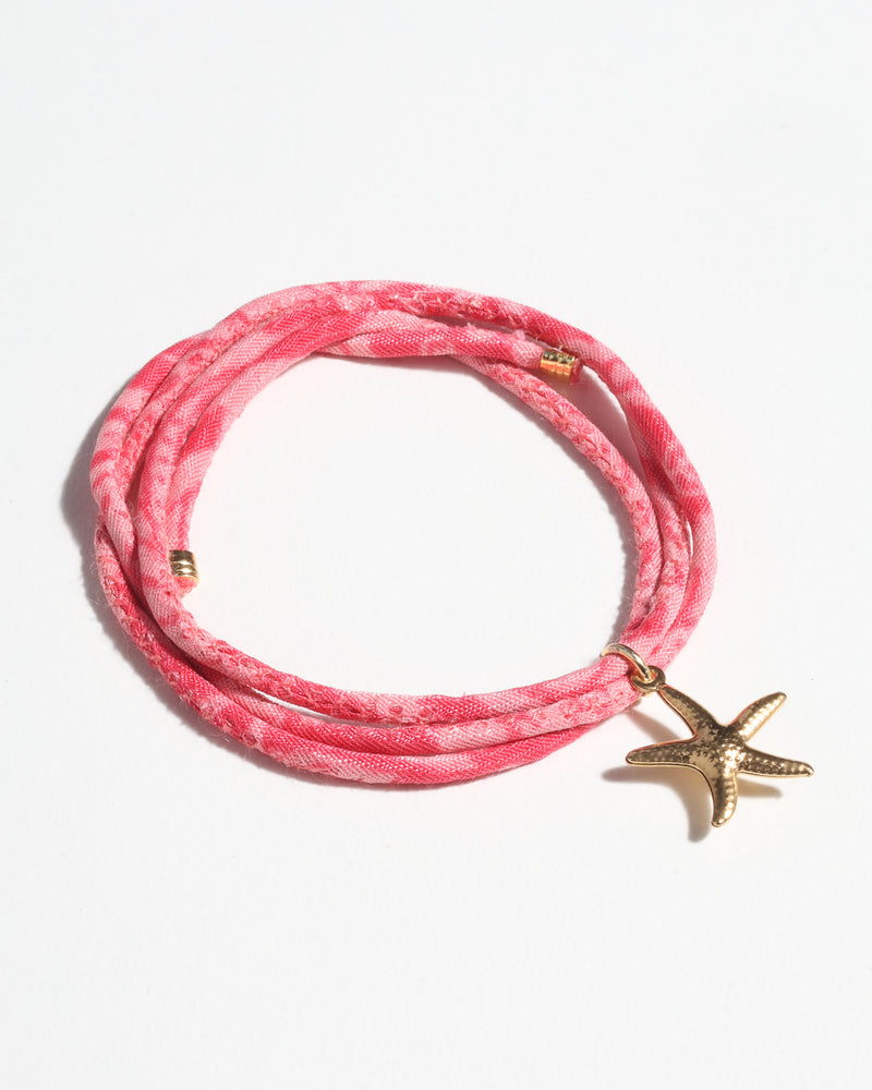 Pink abstract cord bracelet with gold starfish charm, shown flat on white background