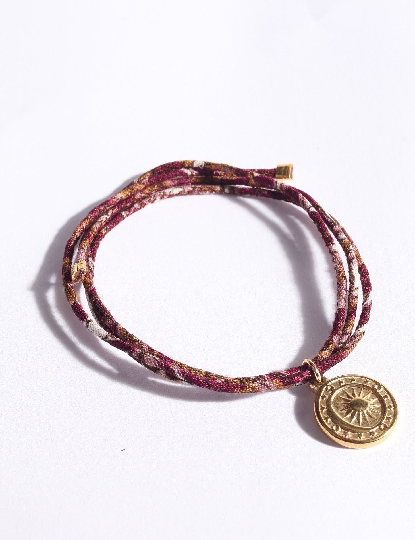 Slim adjustable cord bracelet with gold-plated stainless steel sun charm, inspired by upcycled women’s clothing, sustainable women’s clothing, eco friendly fashion, recycled sustainable fashion, carbon neutral fashion, and environment friendly clothing values.