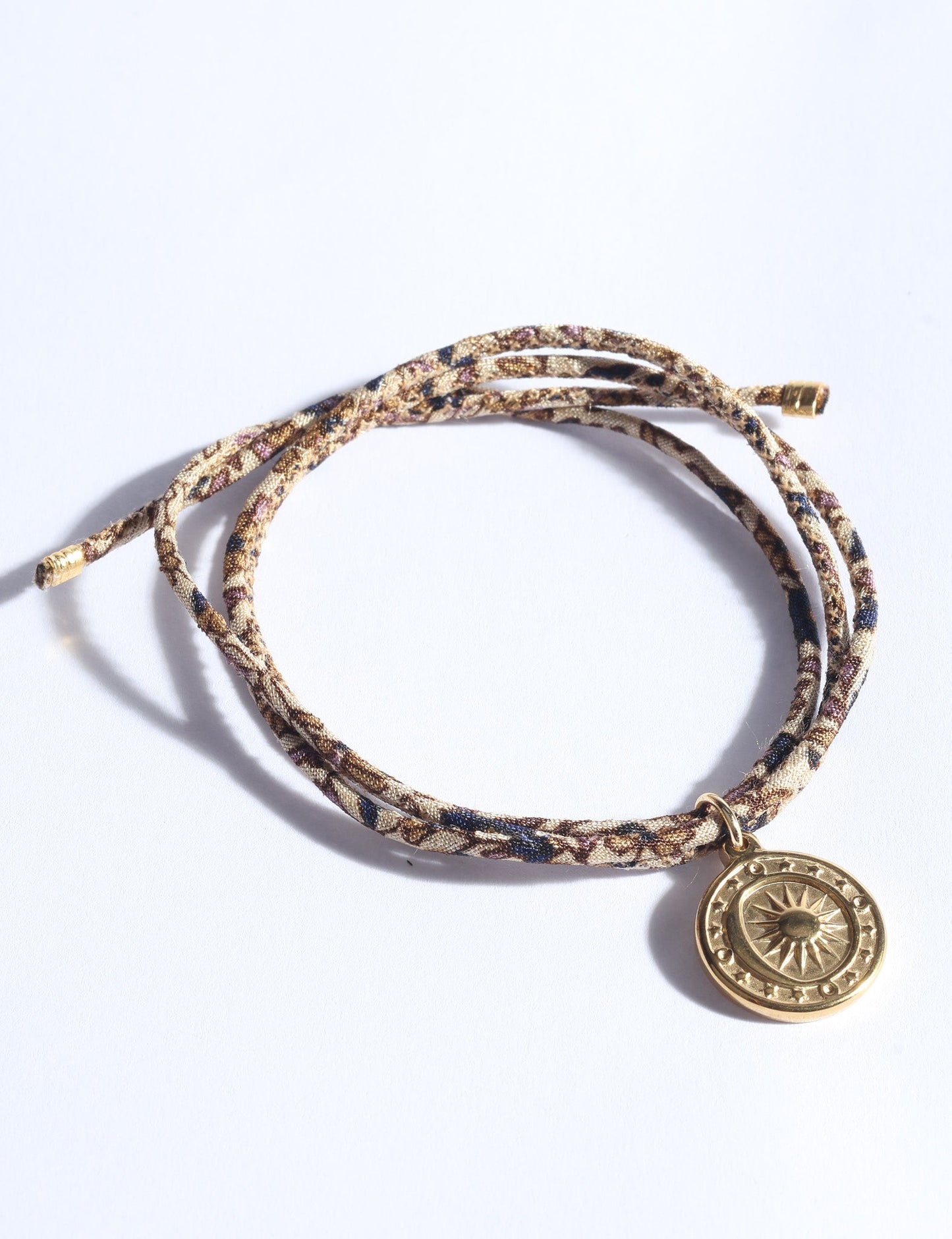 Slim adjustable cord bracelet with gold-plated stainless steel sun charm, inspired by upcycled women’s clothing, sustainable women’s clothing, eco friendly fashion, recycled sustainable fashion, carbon neutral fashion, and environment friendly clothing values.