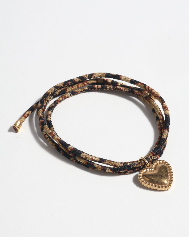 Black tropical patterned cord bracelet with a gold-tone heart-shaped charm, shown flat on a white background