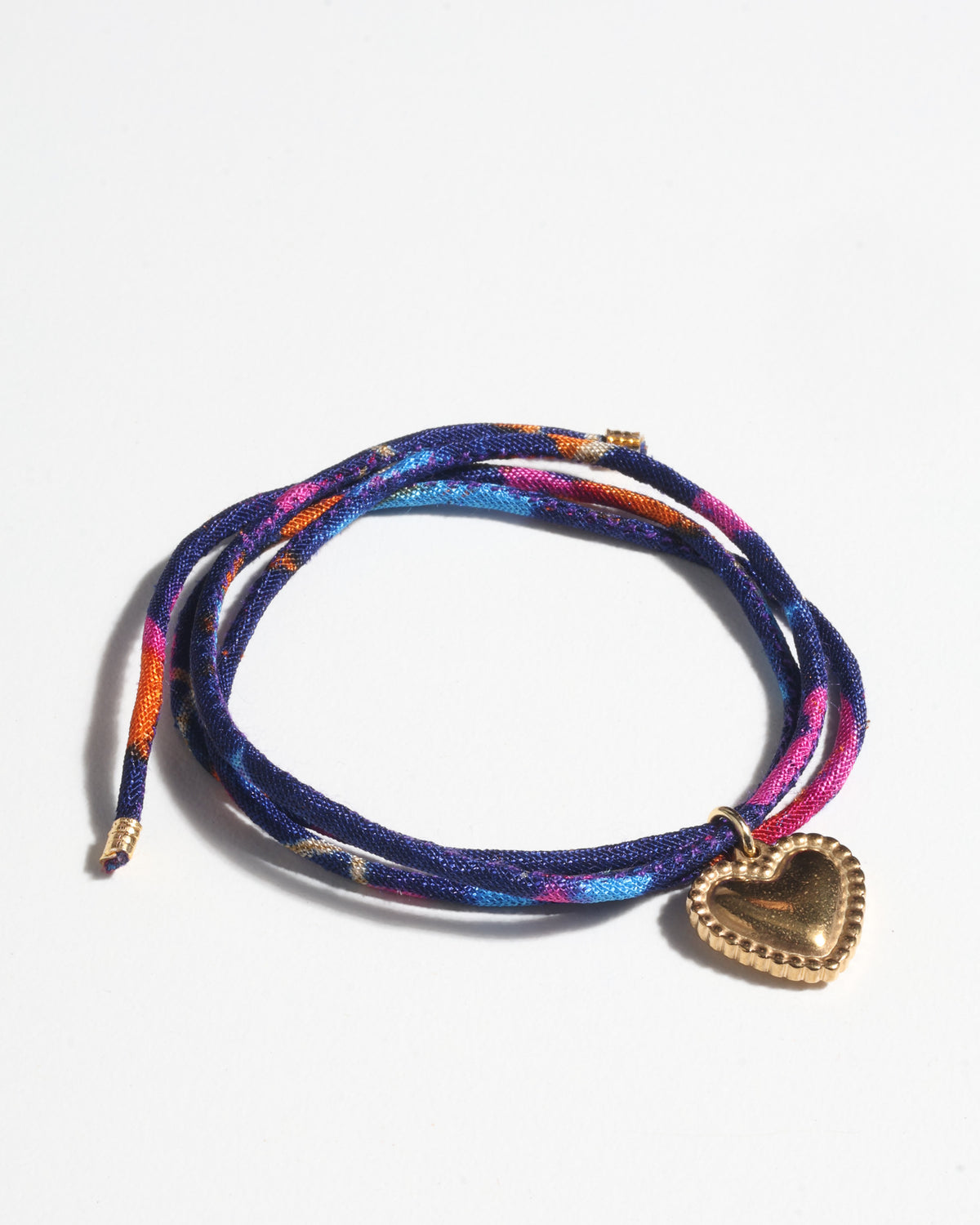 Blue, pink, and orange abstract patterned cord bracelet with a gold-tone heart-shaped charm, shown flat on white background