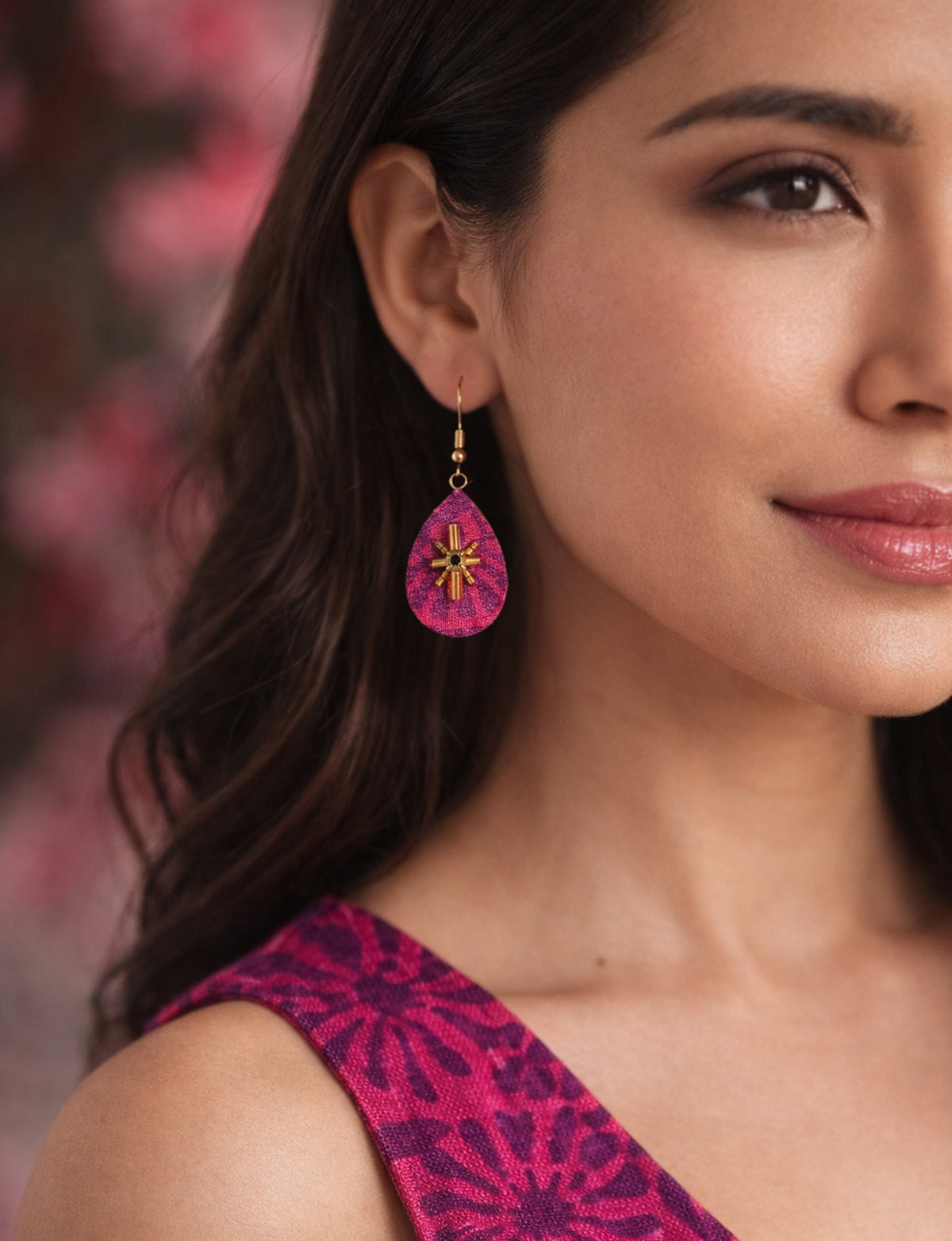 Pink abstract teardrop earrings with gold bead and black center detail worn by model with matching pink patterned top