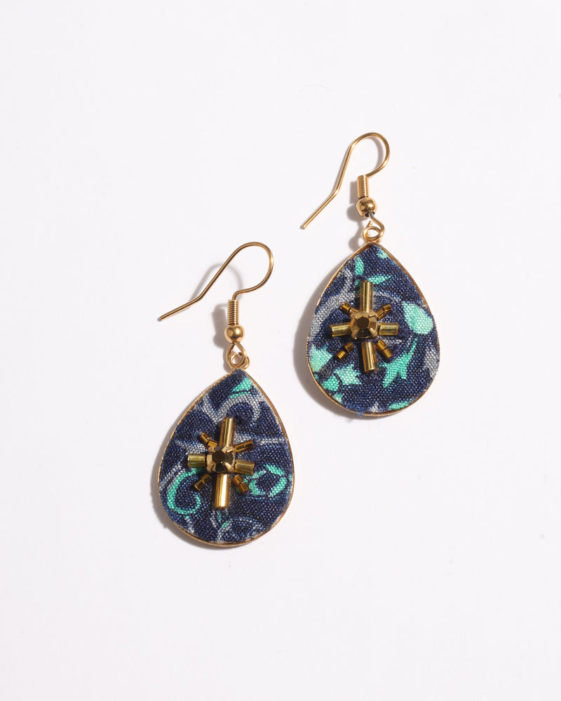 Teardrop-shaped earrings with blue abstract fabric and gold-tone beaded starburst embellishment, shown flat on white background