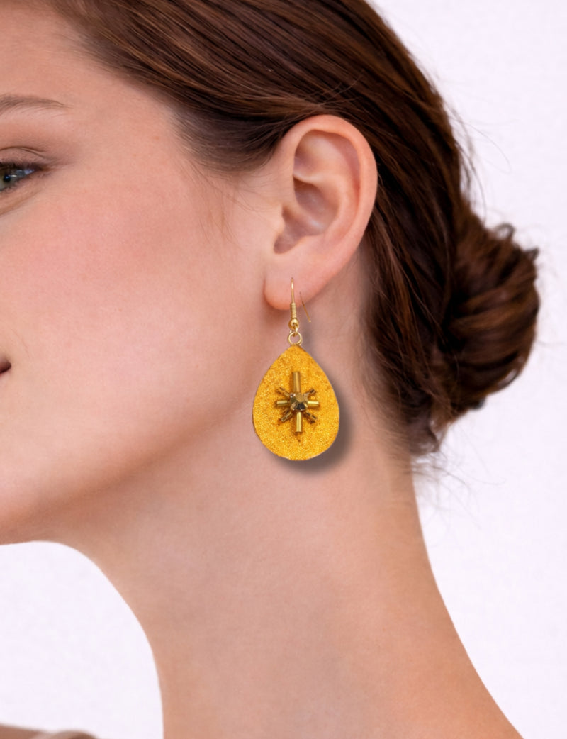 Yellow teardrop-shaped earrings with abstract gold bead design worn on a woman's ear in side profile view