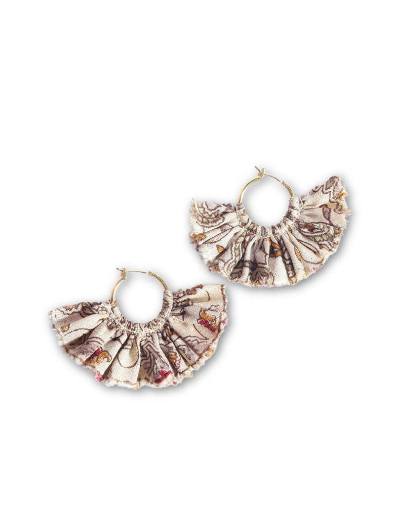 Beige tropical frill fabric hoop earrings with ruffled edges and gold-tone metal hoops, flat lay on white background