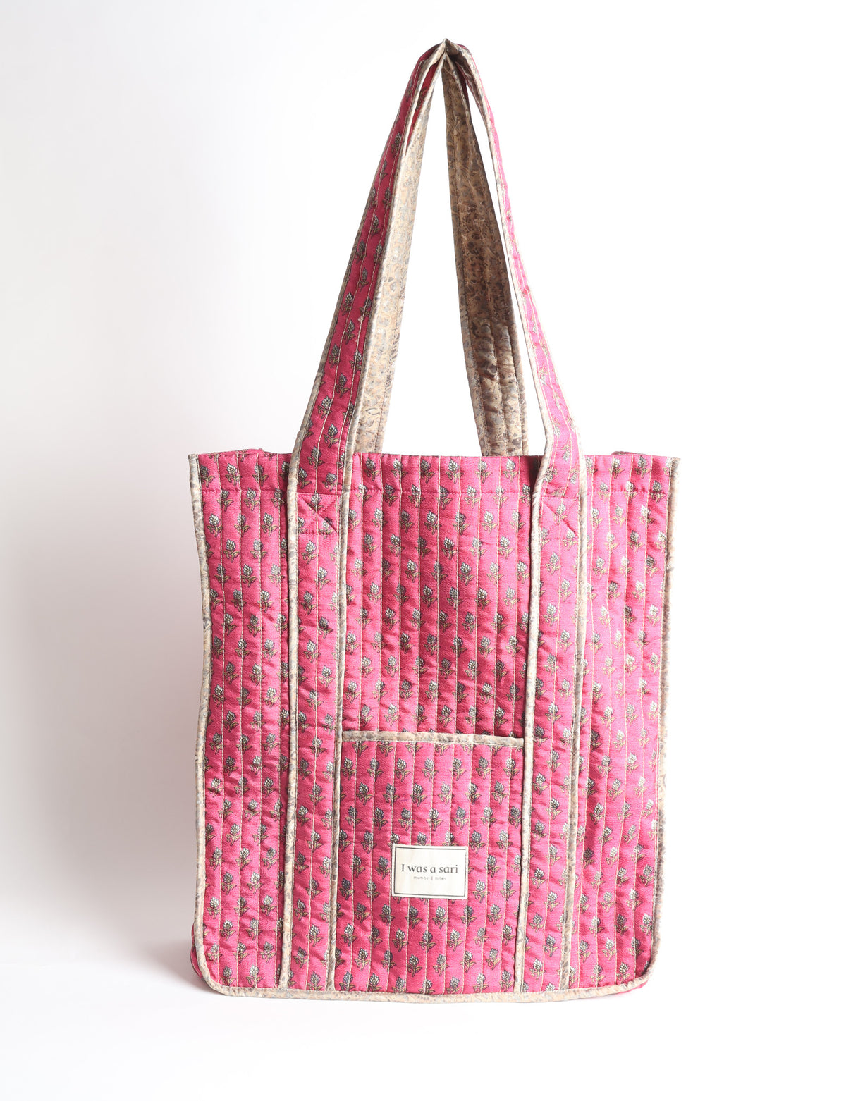 Quilted carry-all tote bag with a structured rectangular shape, long shoulder straps, and an external patch pocket.