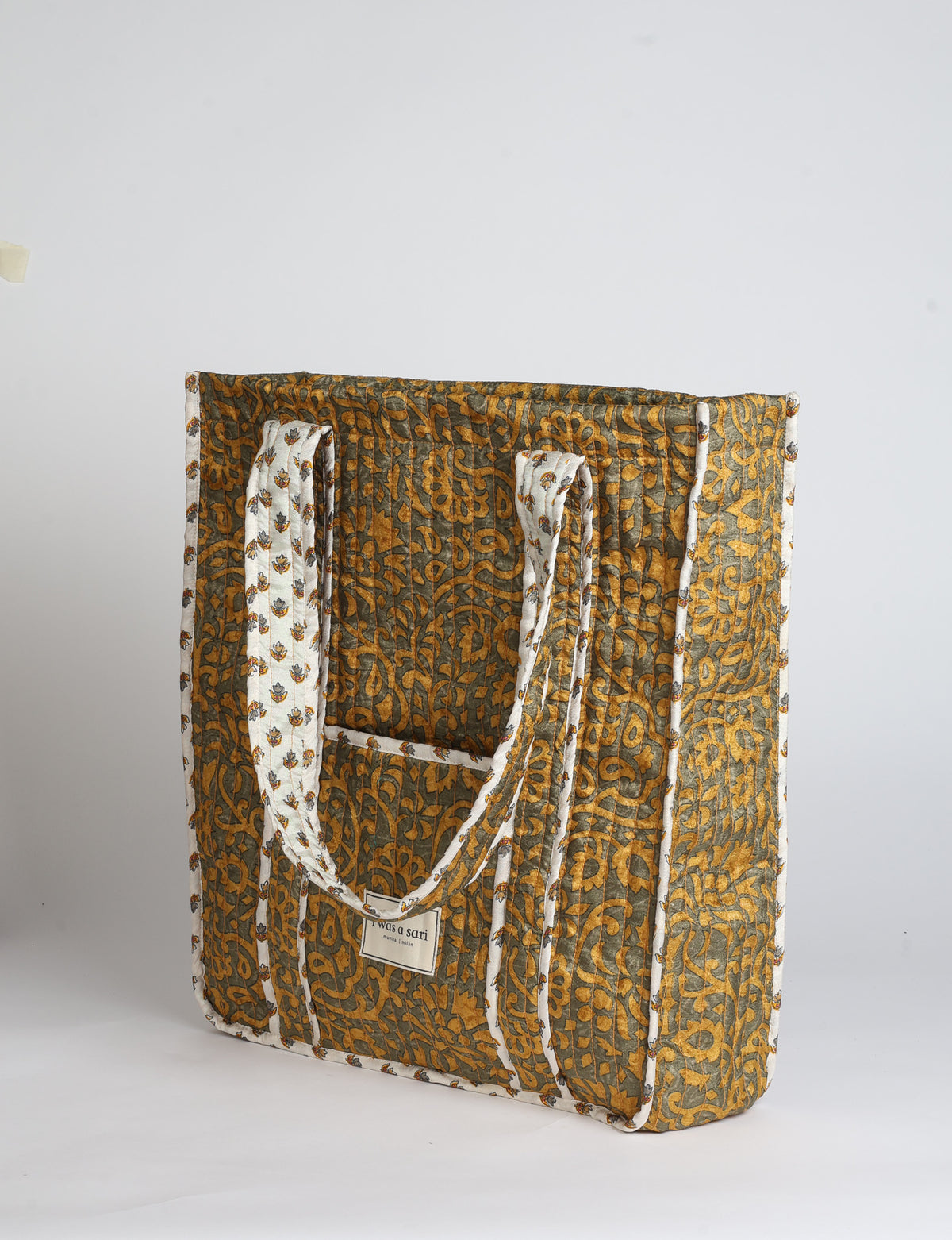 Quilted carry-all tote bag with long shoulder straps, flat base, and external patch pocket.