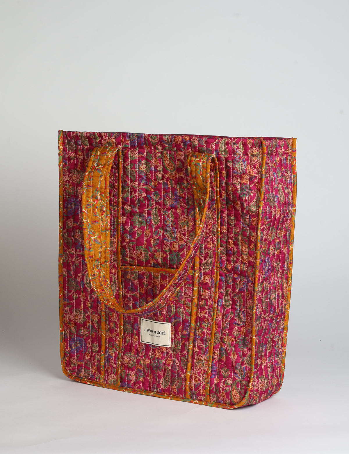 Quilted carry-all tote bag with long shoulder straps, flat base, and external patch pocket.