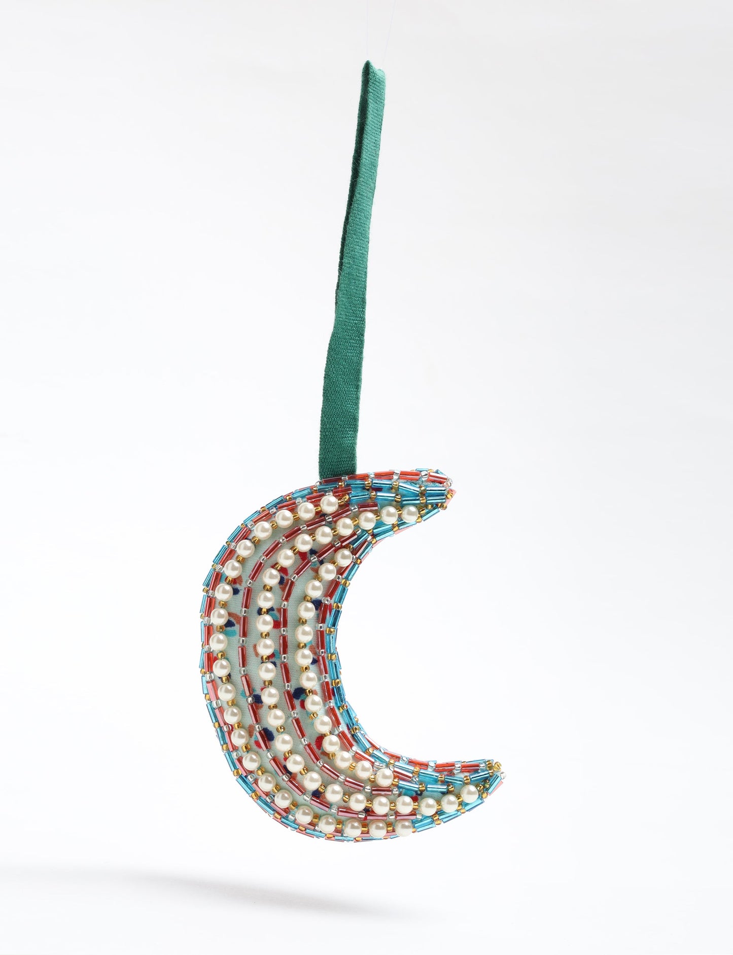 Handcrafted crescent moon-shaped Christmas ornament made from recycled sari fabric, featuring pearls and metallic bead embroidery. A beautiful example of upcycled clothing and fair trade fashion, created through environmentally friendly clothing practices and carbon neutral fashion design.