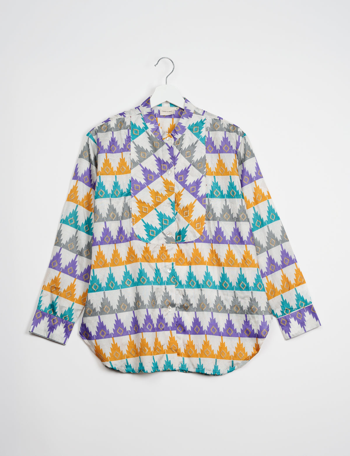 Longline button-up shirt with white base and geometric pattern in purple, orange, teal, and gray, shown flat on hanger