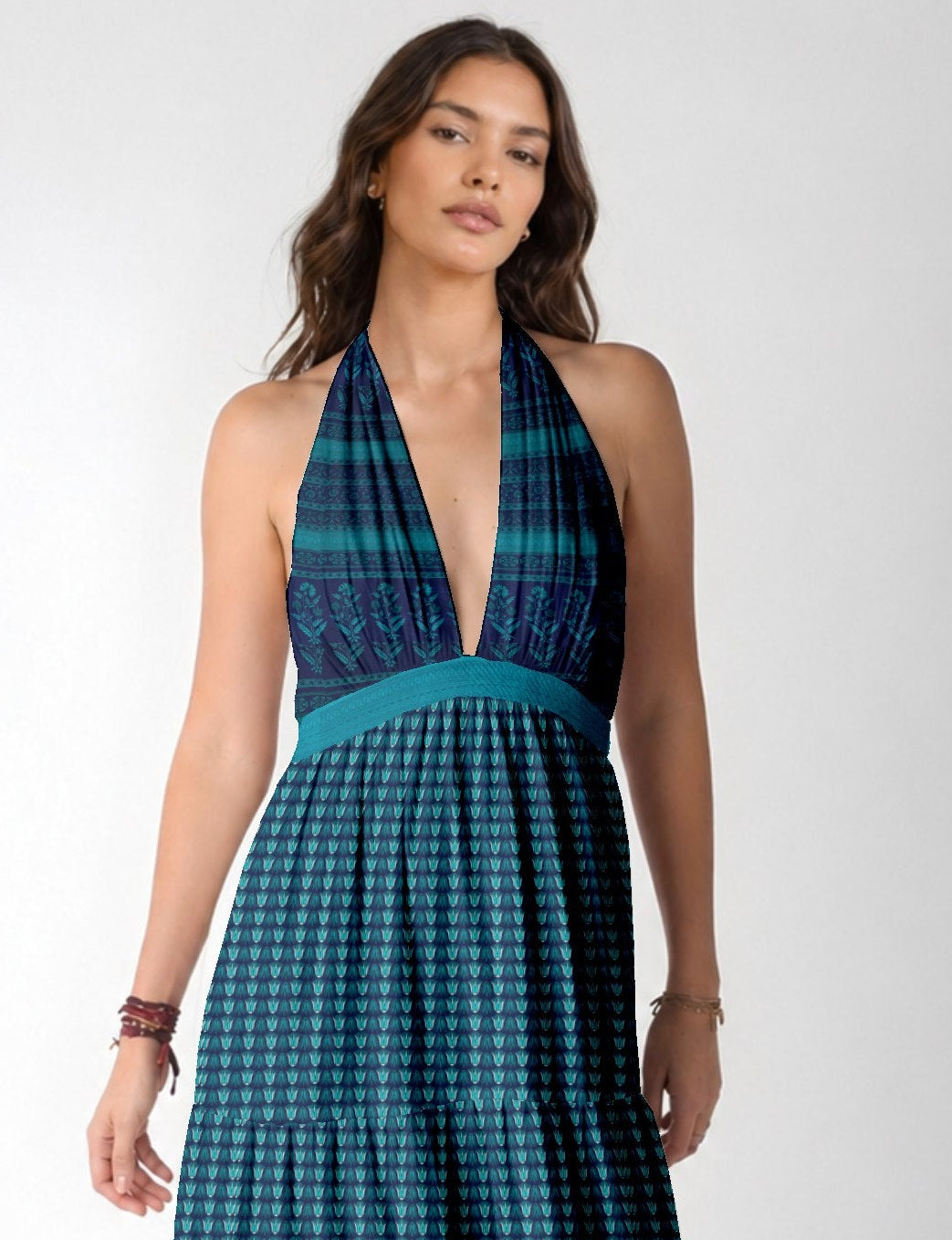 Woman wearing a blue halter maxi dress with tiered skirt and leaf pattern, front view, standing against white background