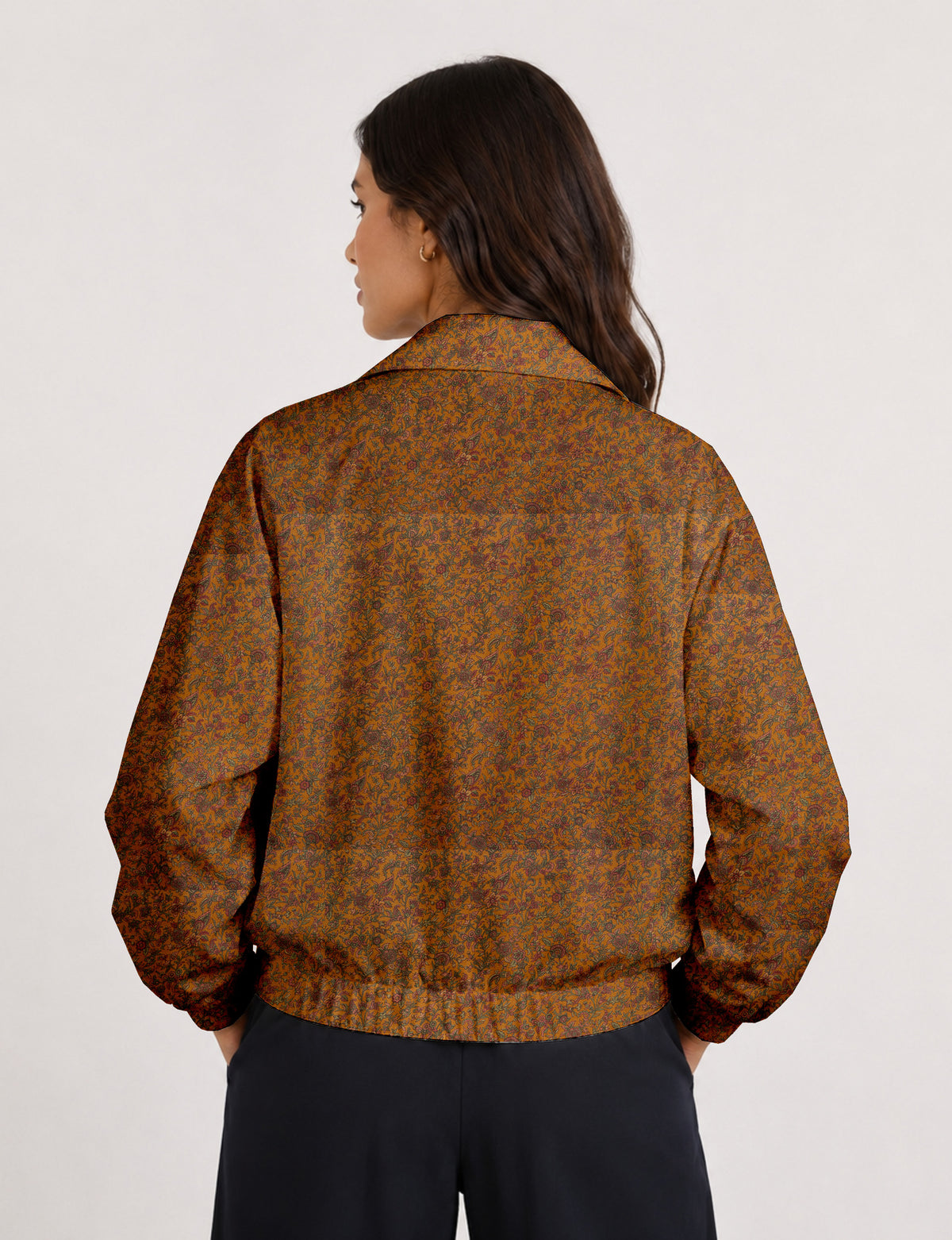 Woman wearing a yellow floral bomber jacket with front zipper, elastic cuffs, and side pockets, shown from front view