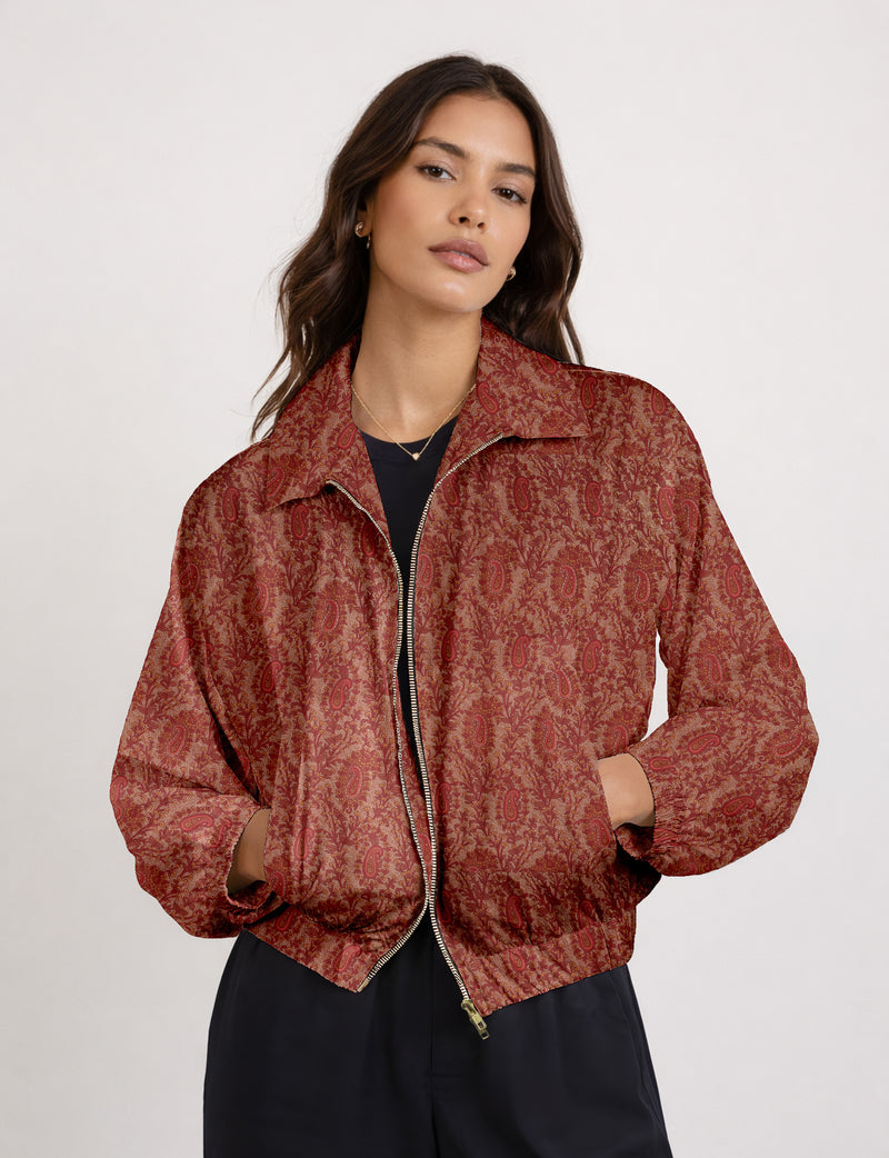 Brown floral bomber jacket with front zipper, elastic cuffs and hem, hanging on white hanger, red floral inner lining visible