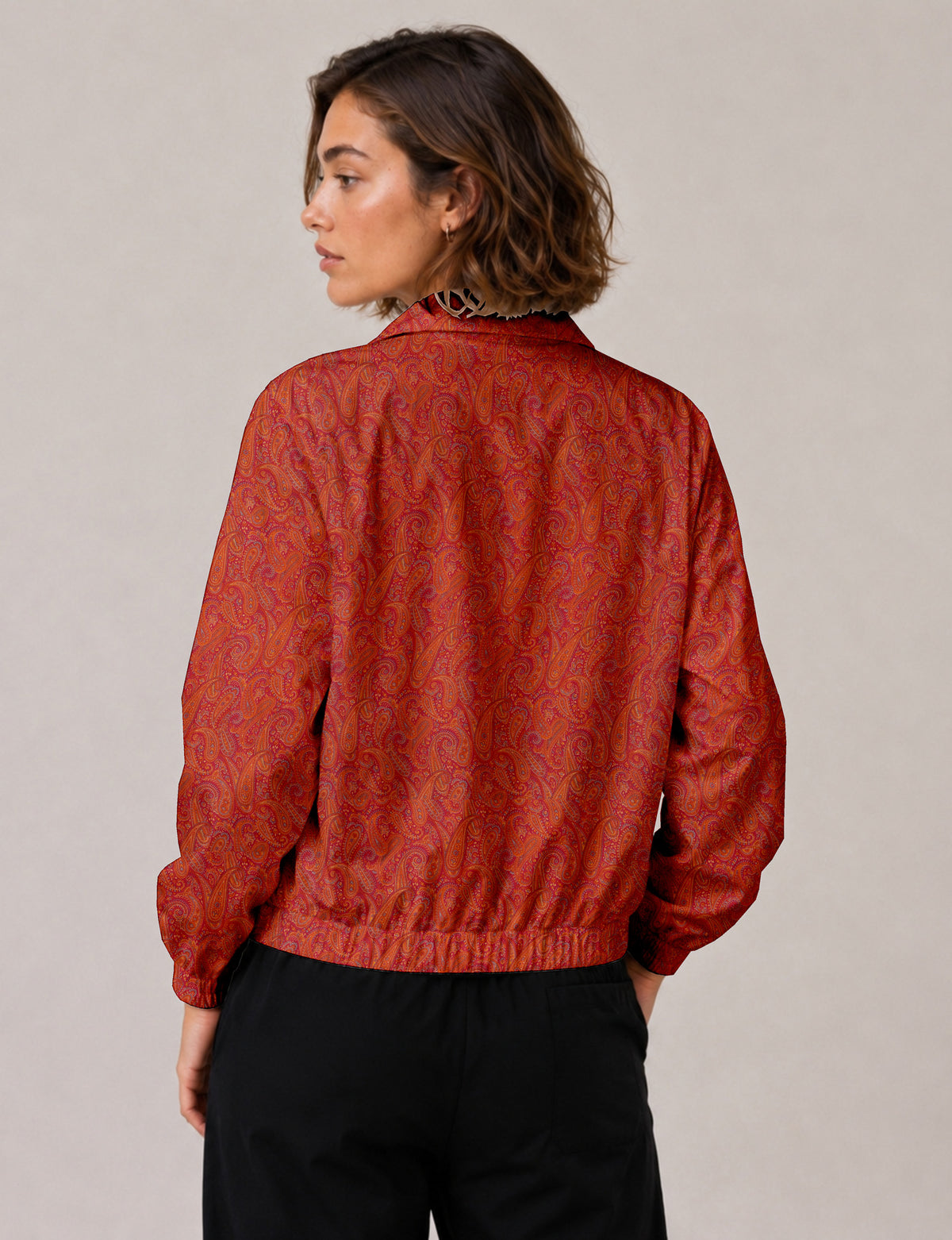 Brown floral bomber jacket with front zipper, elastic cuffs and hem, hanging on white hanger, red floral inner lining visible