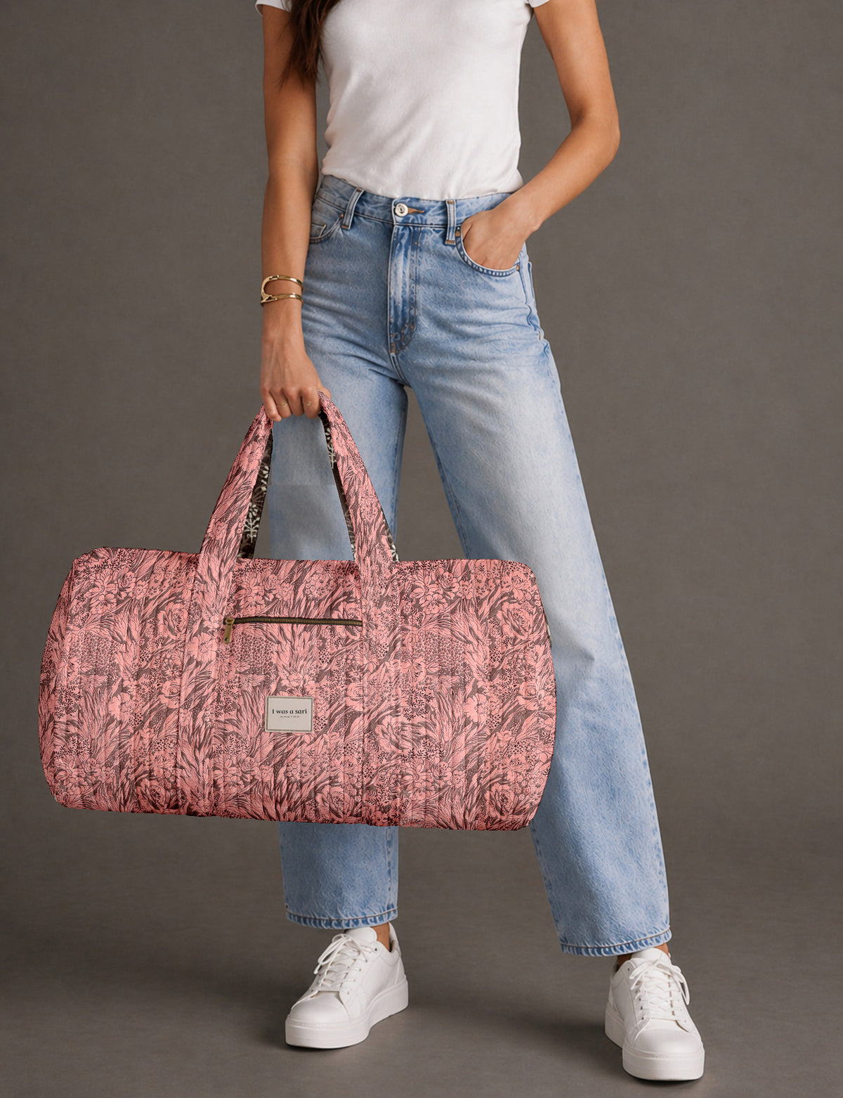 Quilted brown paisley barrel bag with double handles, front pocket, and gold zipper, shown in side angle view