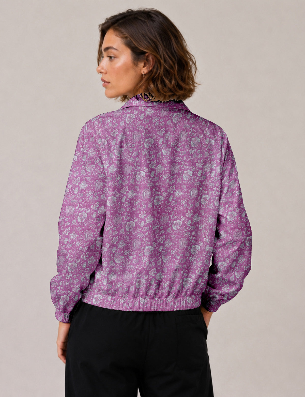 Brown floral bomber jacket with front zipper, elastic cuffs and hem, hanging on white hanger, red floral inner lining visible