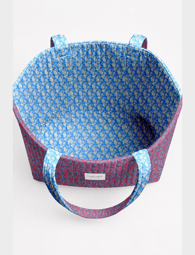 Quilted beach bag with yellow tropical exterior and red patterned interior, shown from top view with handles visible