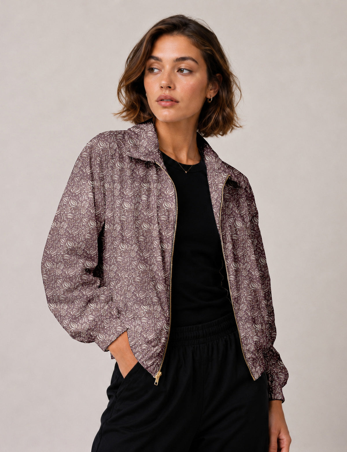 Brown floral bomber jacket with front zipper, elastic cuffs and hem, hanging on white hanger, red floral inner lining visible