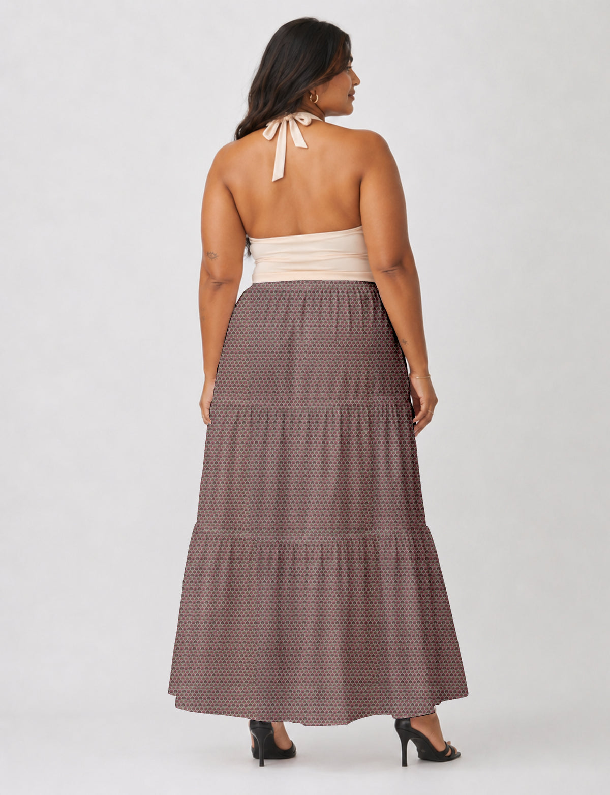 Woman wearing a pink floral midi tiered skirt and beige halter top, shown from back with black heeled sandals