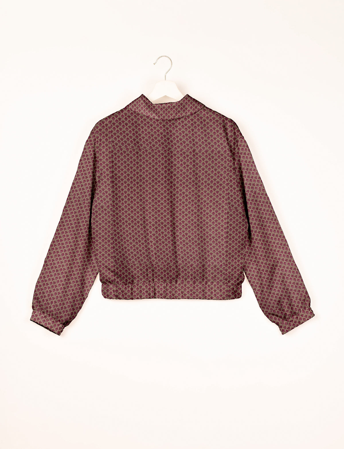 Pink bomber jacket with geometric diamond pattern, long sleeves, elastic cuffs and waistband, shown from back on hanger
