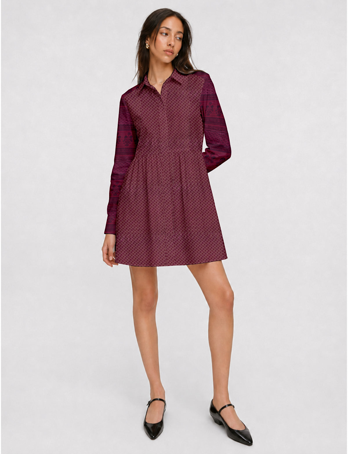 Model wearing a short pink shirt dress with a small leaf pattern, long sleeves, collar, and black Mary Jane shoes