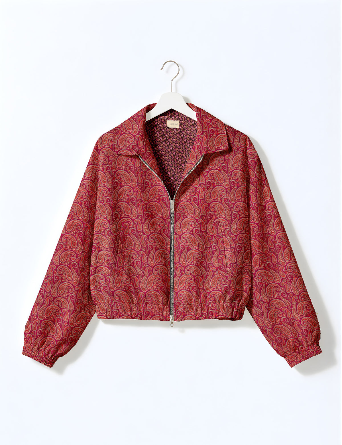 Brown floral bomber jacket with front zipper, elastic cuffs and hem, hanging on white hanger, red floral inner lining visible