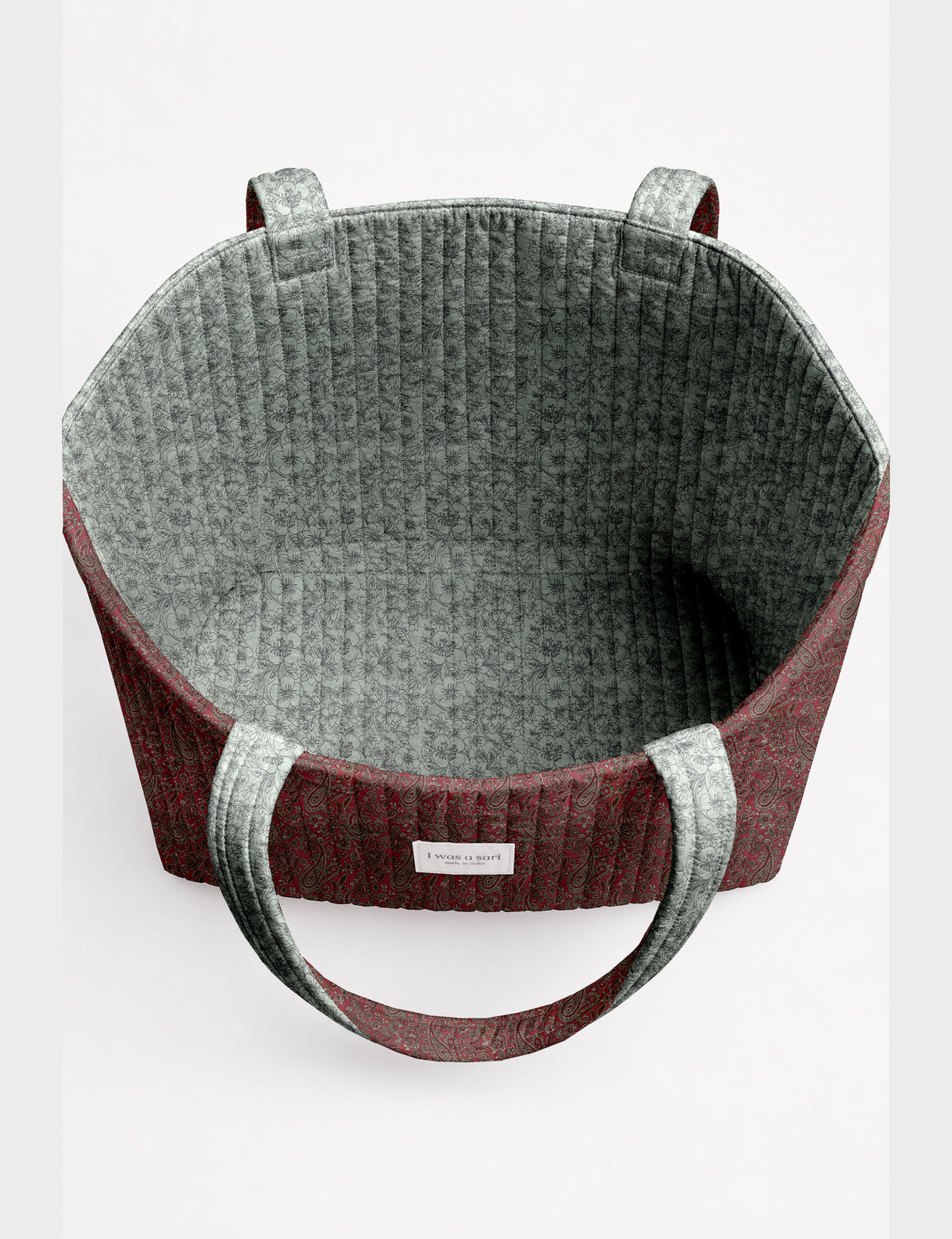 Quilted beach bag with yellow tropical exterior and red patterned interior, shown from top view with handles visible