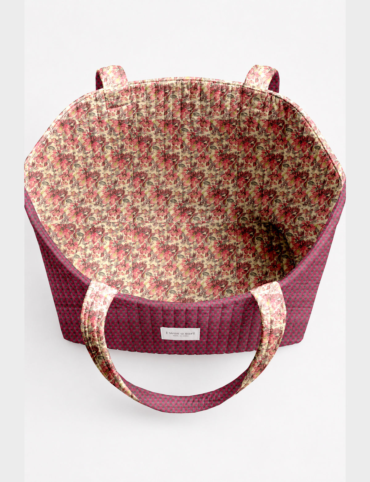 Quilted beach bag with yellow tropical exterior and red patterned interior, shown from top view with handles visible
