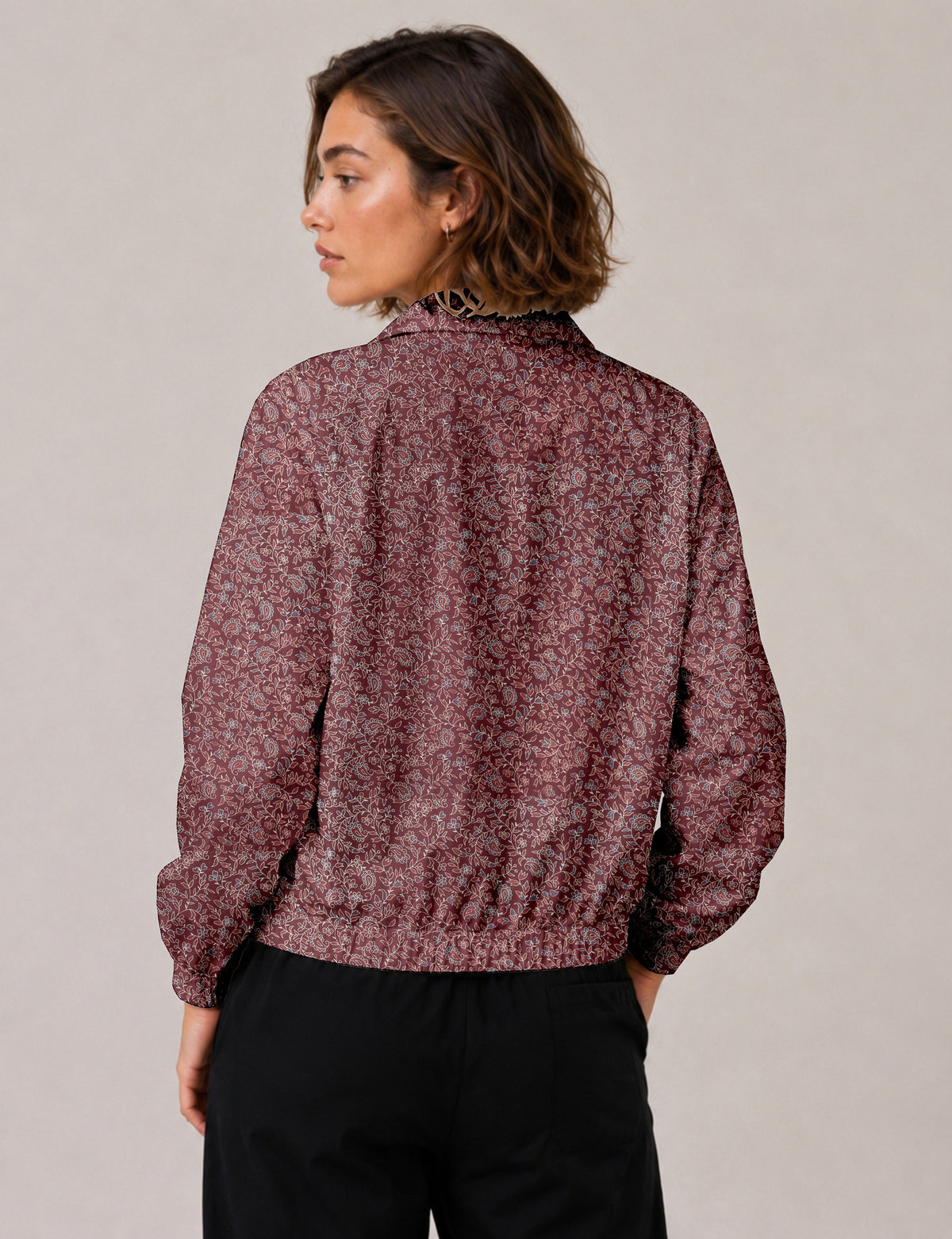 Brown floral bomber jacket with front zipper, elastic cuffs and hem, hanging on white hanger, red floral inner lining visible