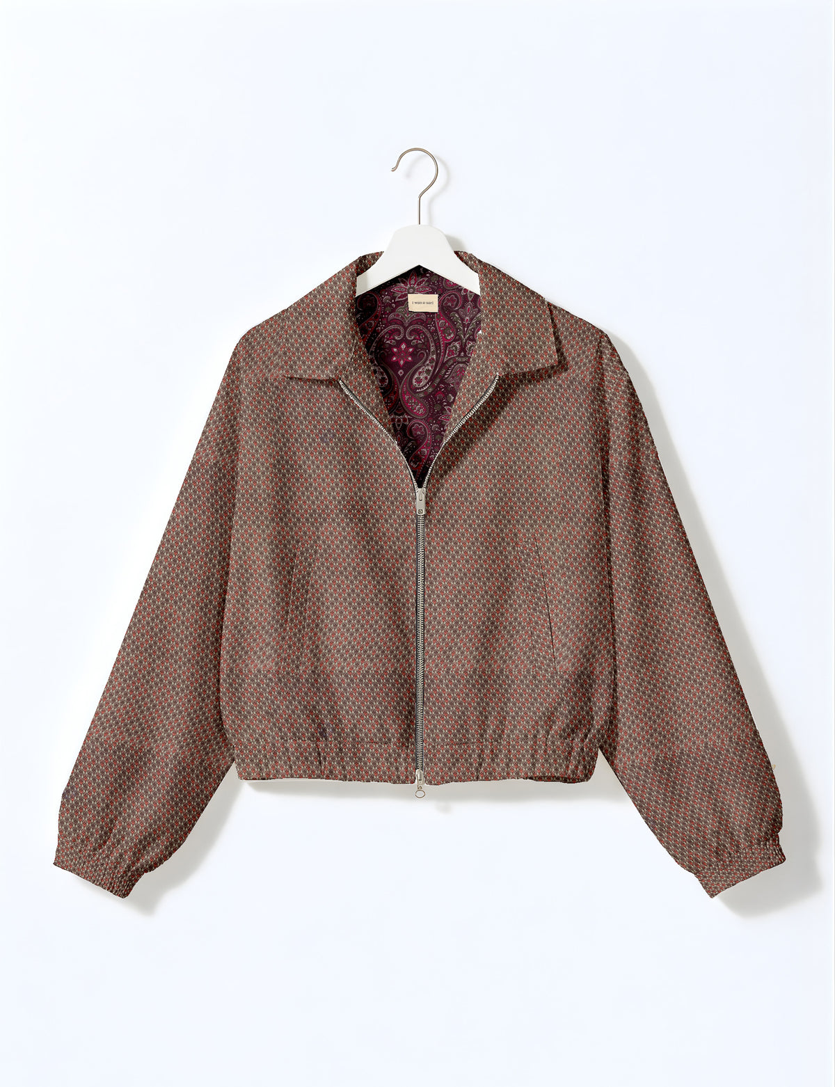 Brown floral bomber jacket with front zipper, elastic cuffs and hem, hanging on white hanger, red floral inner lining visible