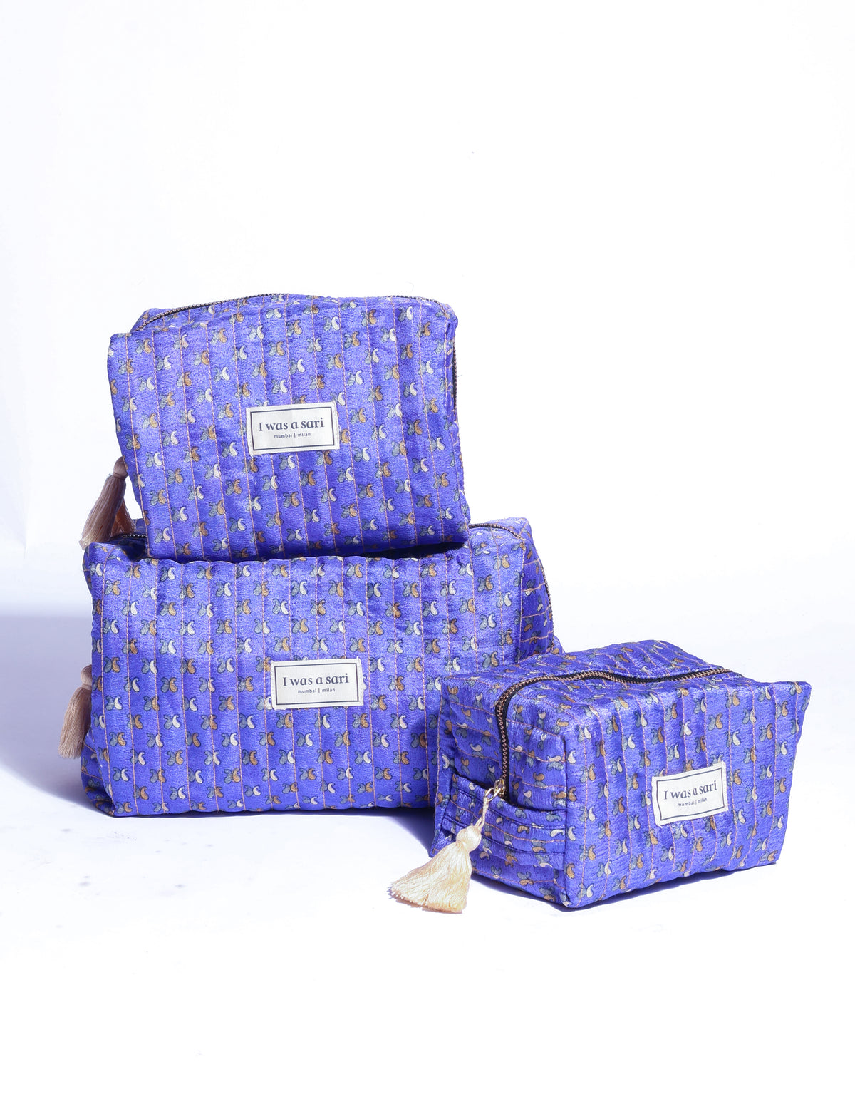 Purple quilted utility pouch with micro floral pattern, zipper closure, tassel detail, and "I was a sari" label, front view