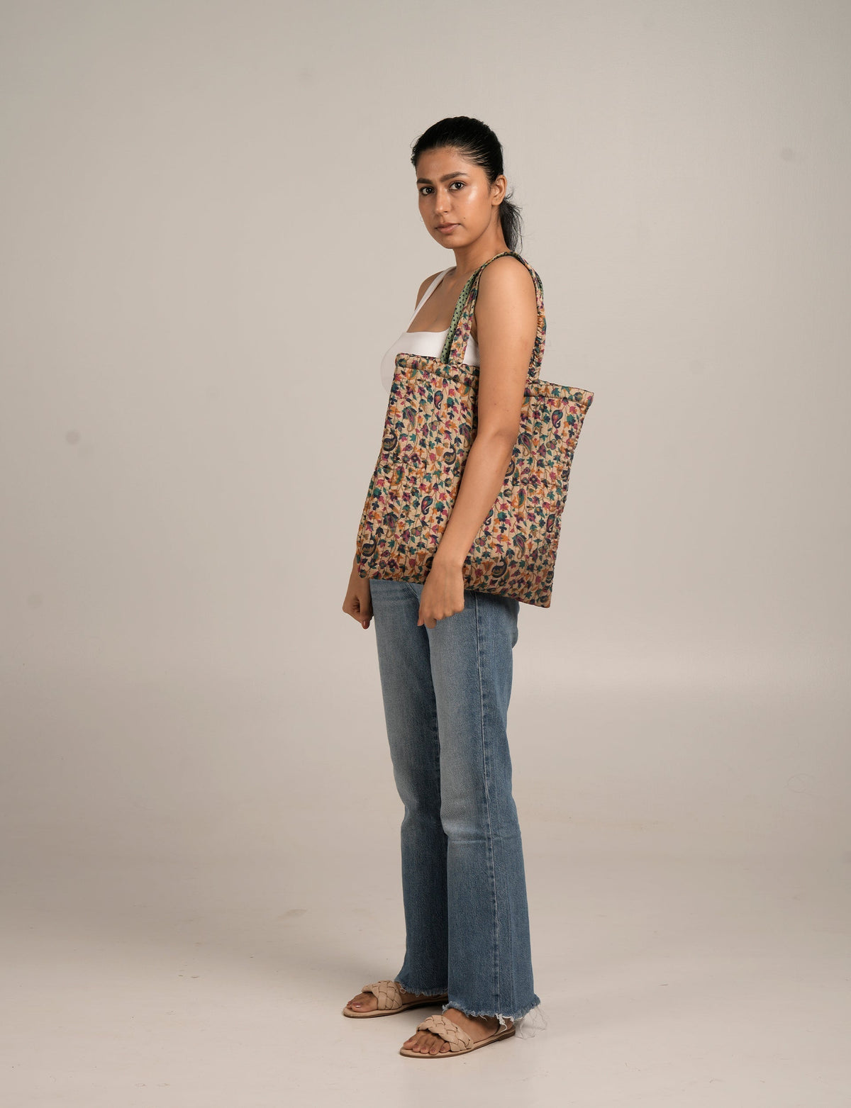 Woman wearing a pink tropical quilted shopper bag with floral pattern over shoulder, side view