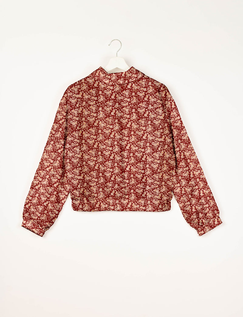 Red floral bomber jacket with long sleeves and elastic cuffs, shown from back on white hanger against white background