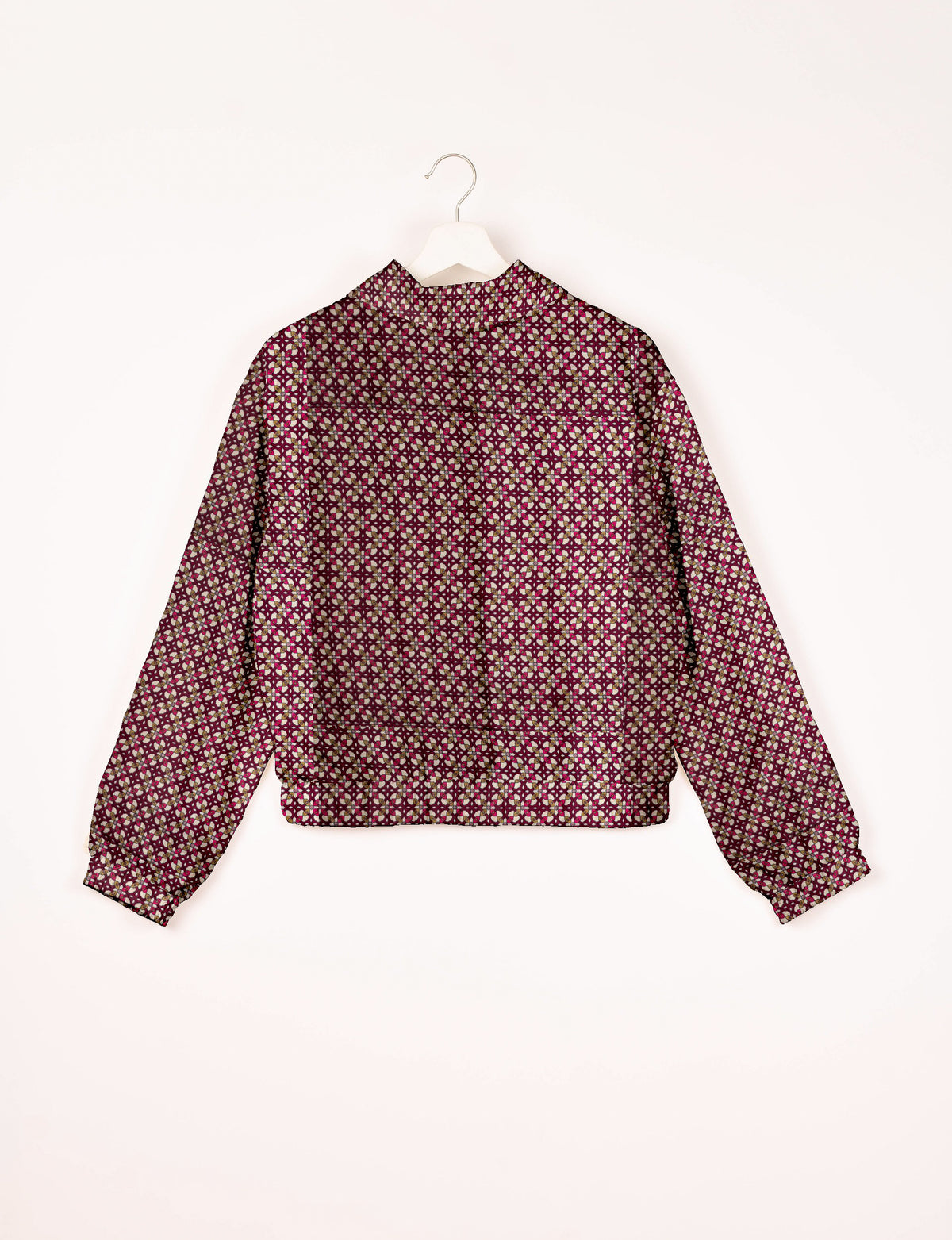 Red bomber jacket with geometric pattern in white, beige, and dark red, shown from back on white hanger
