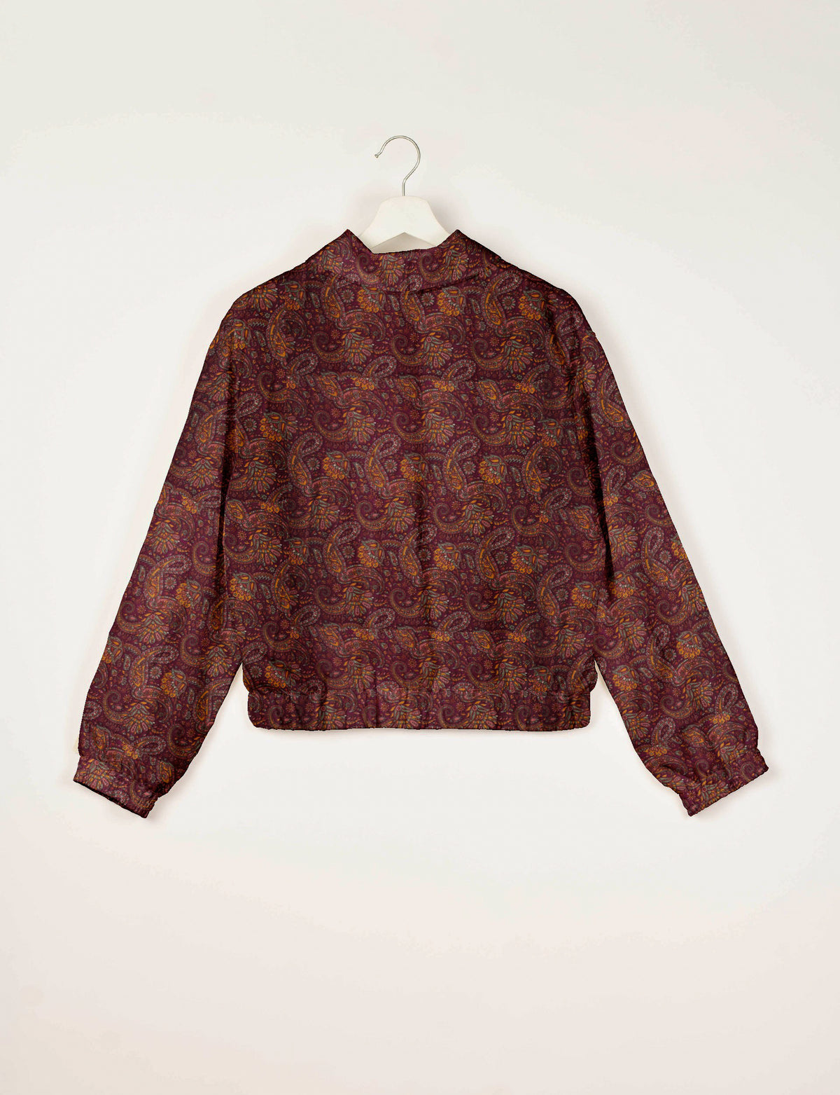 Red paisley patterned bomber jacket with elastic cuffs and waistband, shown from back on white hanger