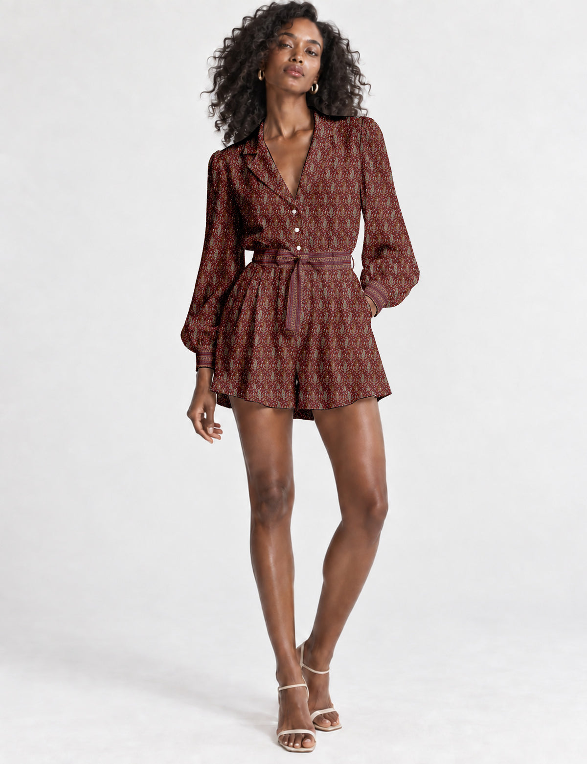 Women’s long sleeve playsuit with wrap-style front, V neckline, notched collar, adjustable waist tie and mid-thigh shorts.