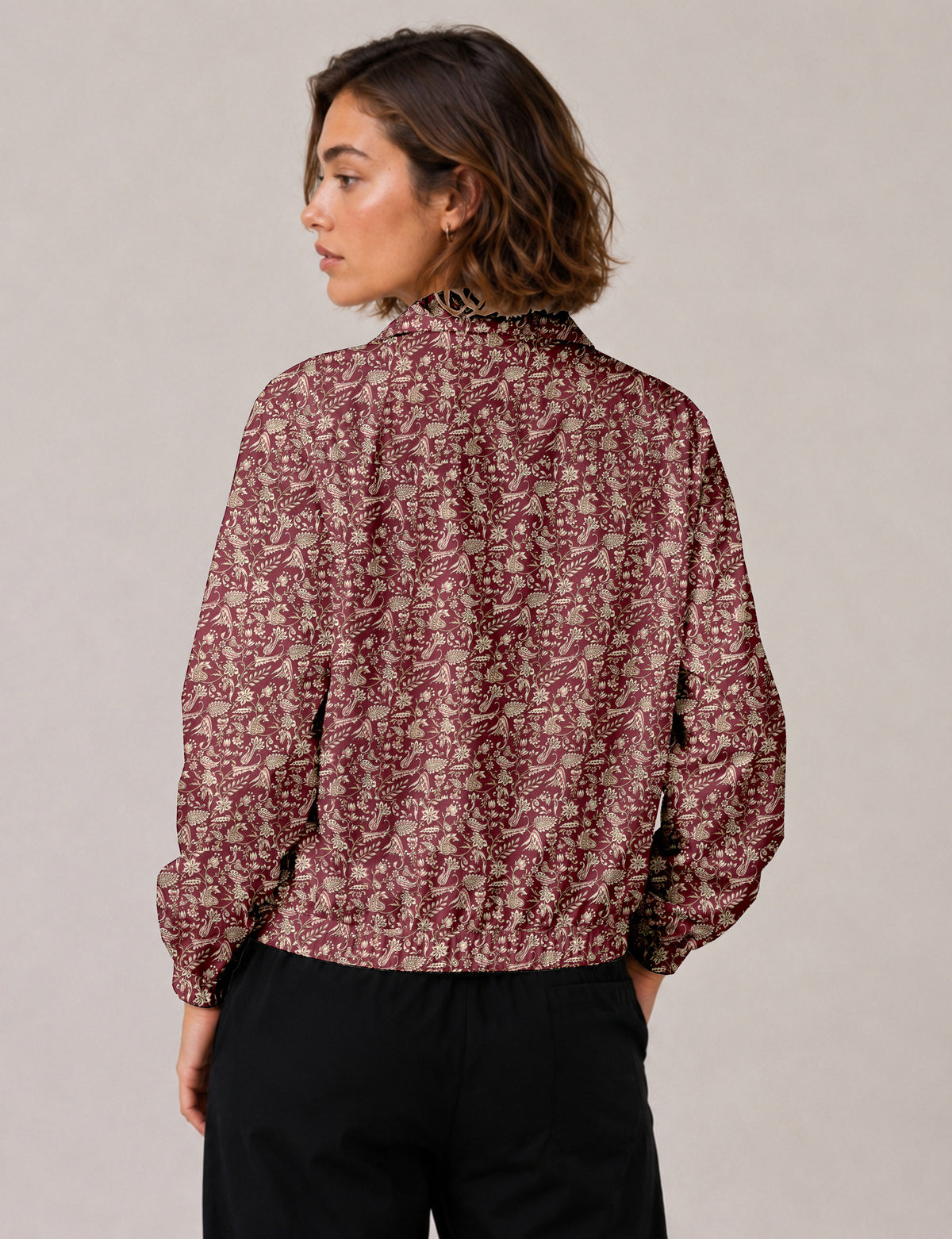 Brown floral bomber jacket with front zipper, elastic cuffs and hem, hanging on white hanger, red floral inner lining visible