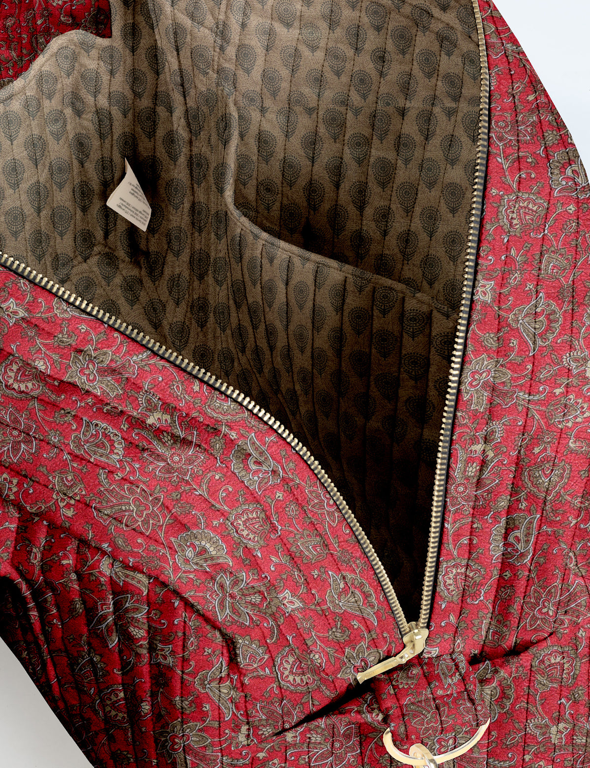 Brown quilted duffle bag with paisley pattern, front zip pocket, dual handles, and label reading "I was a sari"