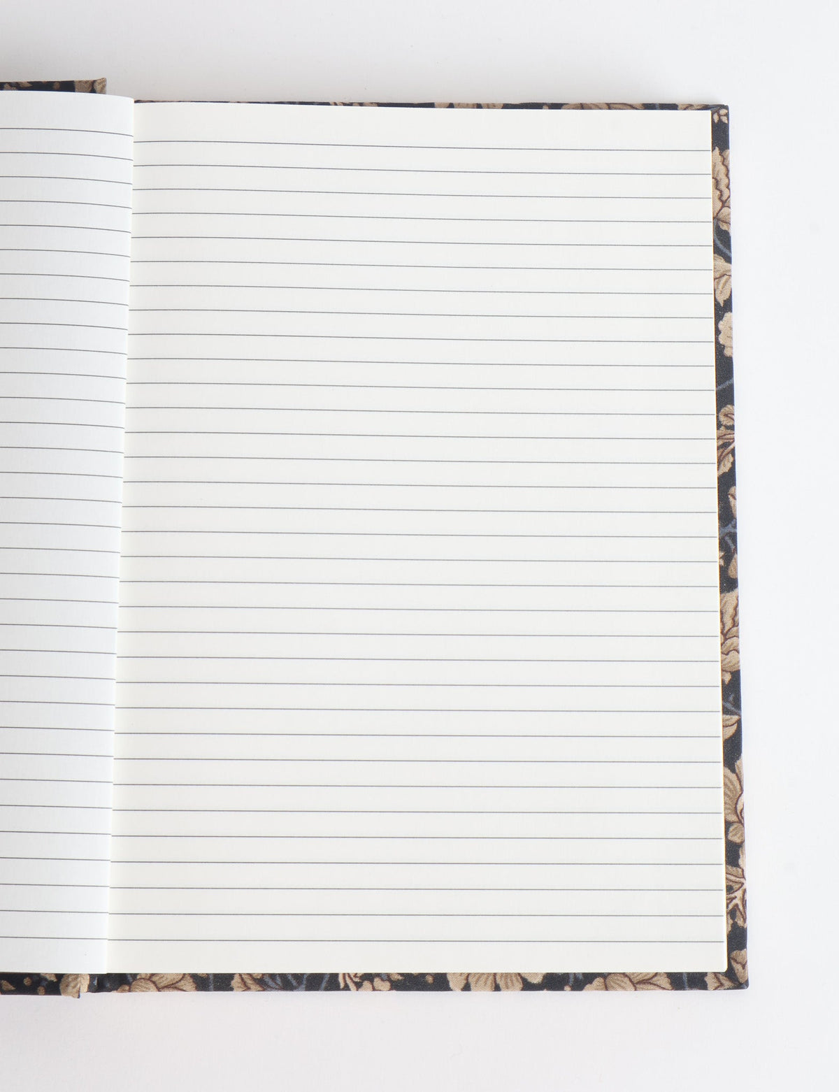 Open notebook with lined white pages and a dark floral-patterned hard cover visible at edges, flat lay view