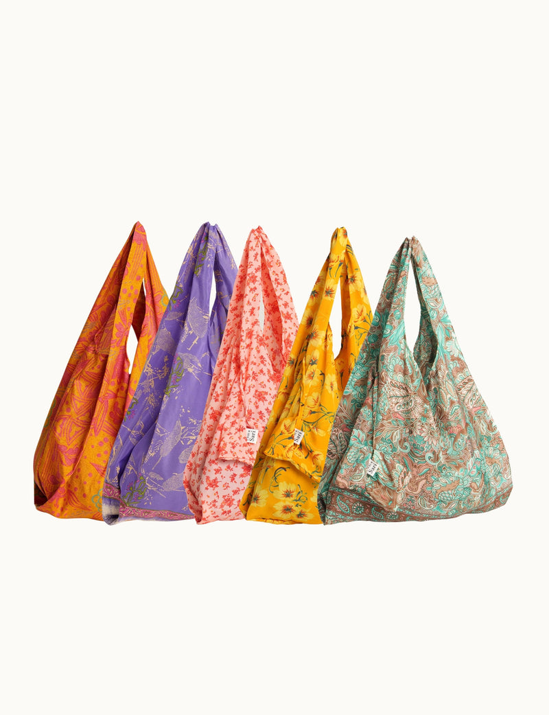 Set of five reusable fabric bags in orange, purple, pink, yellow, and teal with floral and paisley patterns hanging upright