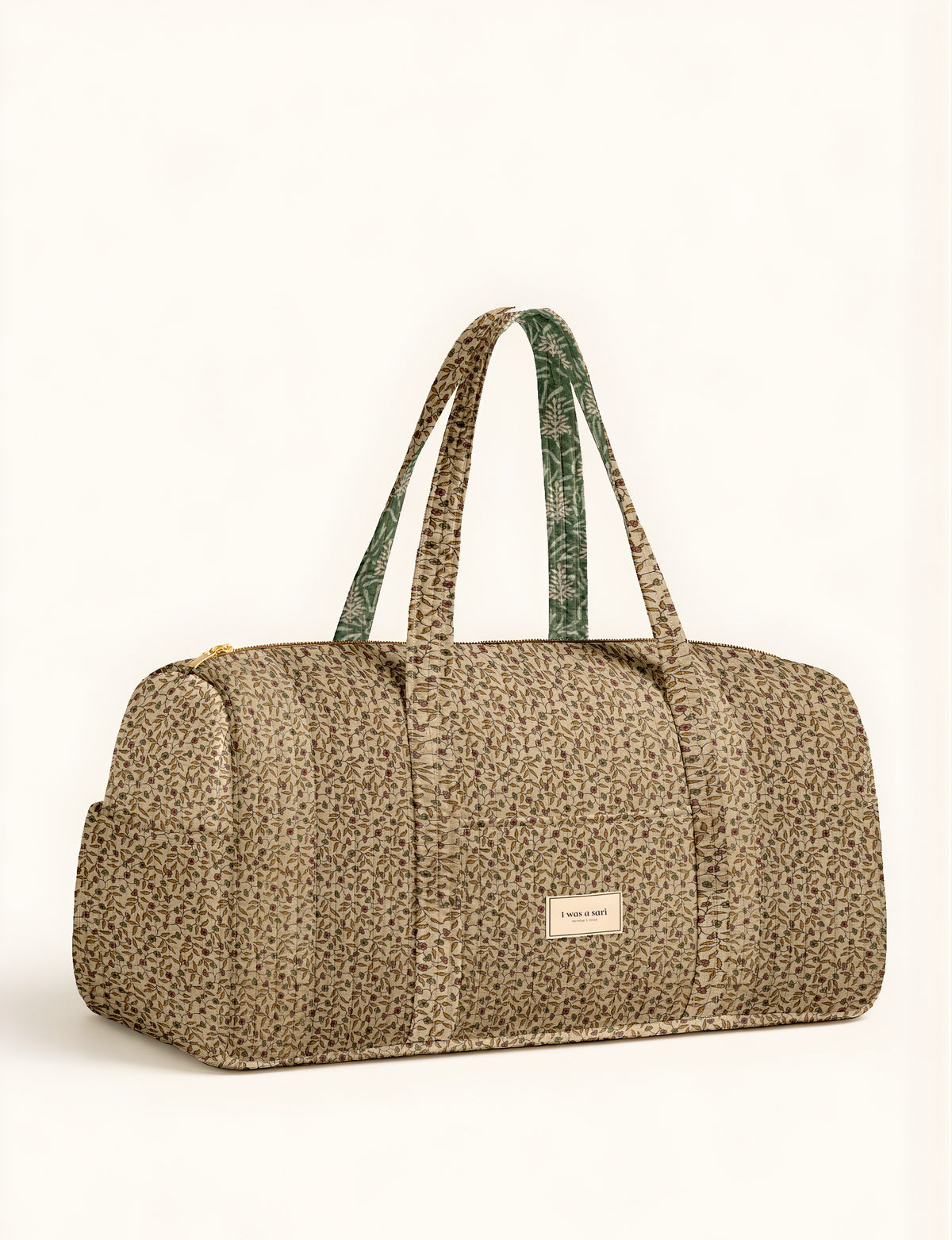 Beige and green floral patterned duffle travel bag with dual handles and front pocket, label reads "I was a sari"
